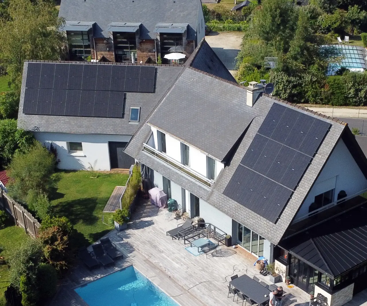 Vue aérienne d'une maison équipée de panneaux solaires avec piscine, installation réalisée par Alvéa Solaire