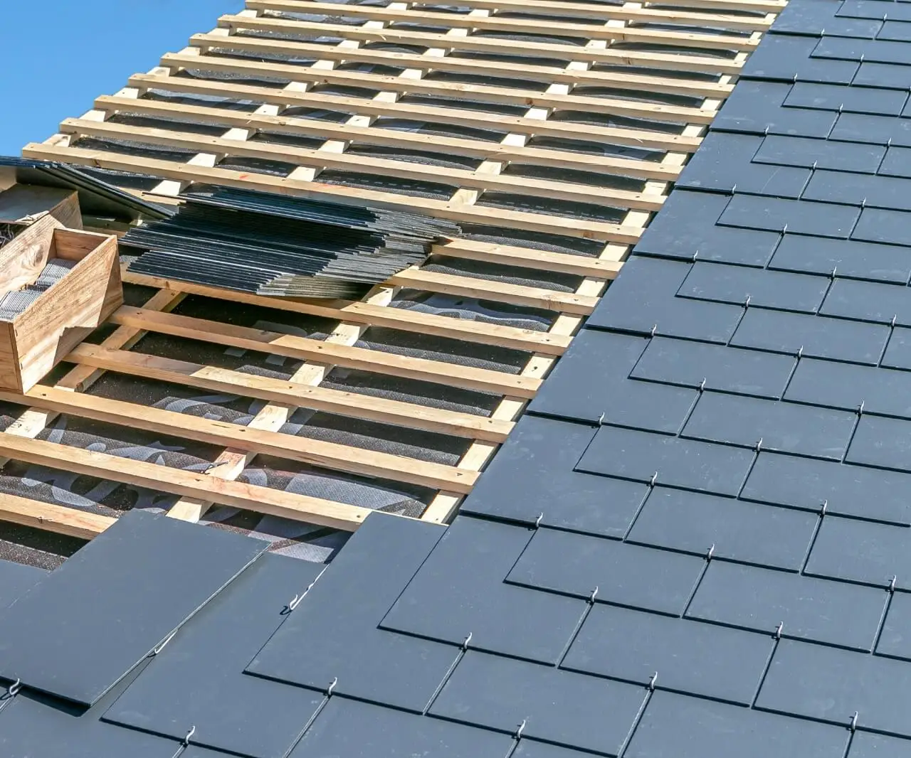 Pose d'ardoises sur toiture en préparation d'une installation de panneaux solaires par Alvéa Solaire